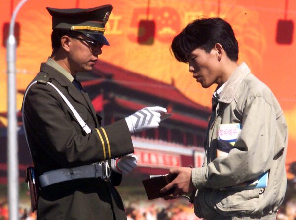 Một công an kiểm tra giấy tờ tùy thân của một người đàn ông trên đường phố ở Bắc Kinh, Trung Quốc vào ngày 29/09/1999. (Ảnh: Stephen Shaver/AFP qua Getty Images)