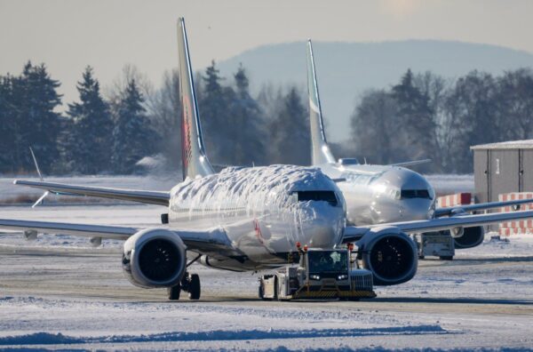 Một chiếc đầu kéo đang di chuyển một chiếc phi cơ của Air Canada phủ đầy tuyết và băng trong khi một chiếc phi cơ của Westjet đang di chuyển phía sau tại Phi trường Quốc tế Vancouver ở Richmond, British Columbia, Canada, hôm 21/12/2022. (Ảnh: The Canadian Press/Darryl Dyck)