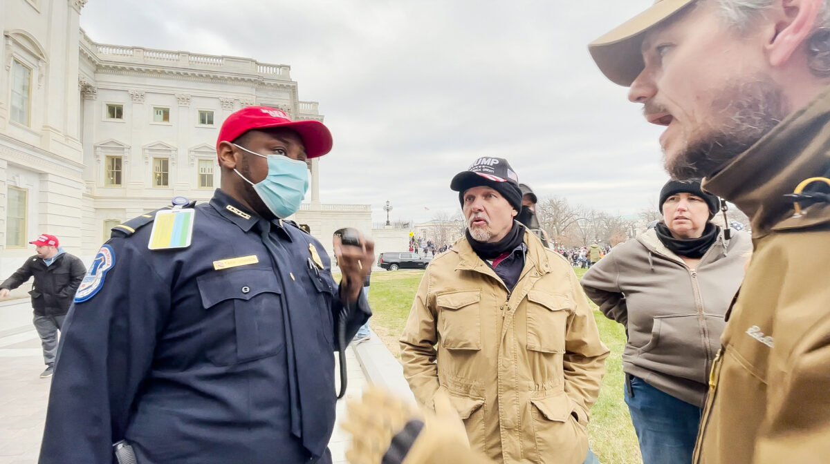 Trung úy Cảnh sát Điện Capitol Hoa Kỳ Tarik Khalid Johnson nhờ những người trong nhóm Oath Keepers là ông Steve (giữa) và ông Michael Nichols giúp giải cứu các sĩ quan cảnh sát bị mắc kẹt bên trong Điện Capitol vào ngày 06/01/2021. (Ảnh: Rico La Starza/Thuộc đặc quyền The Epoch Times)