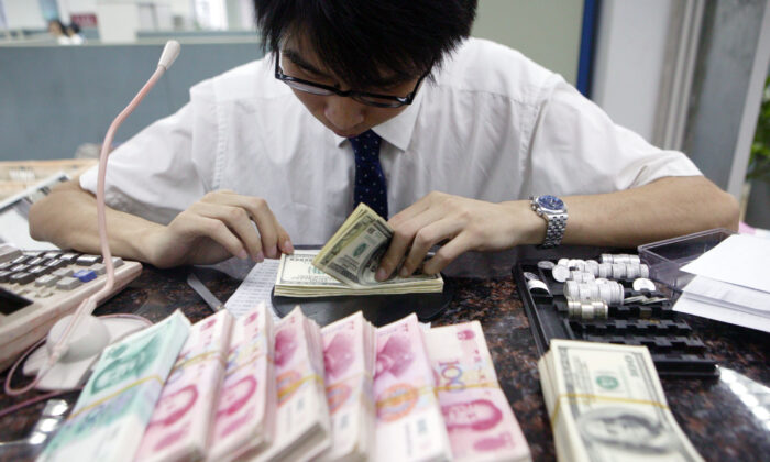 Một nhân viên đếm những chồng nhân dân tệ Trung Quốc và USD tại một ngân hàng ở Thượng Hải, vào ngày 22/07/2005. (Ảnh: China/Getty Images)