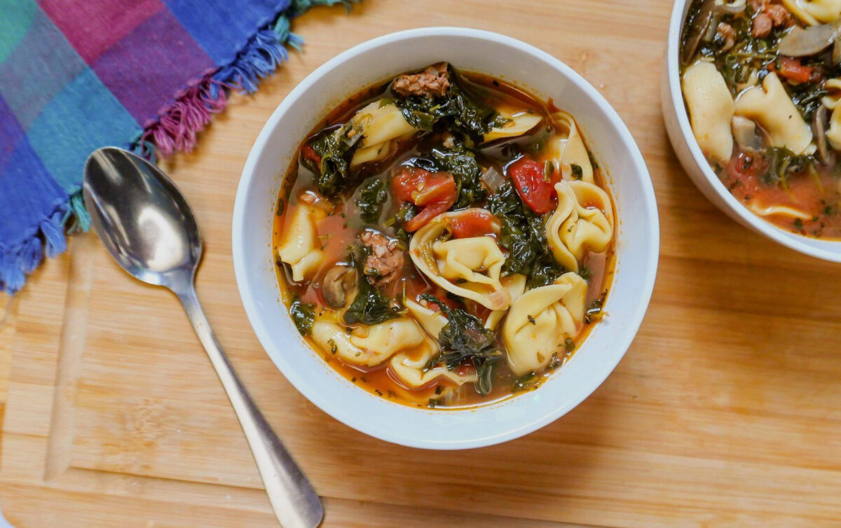 Món súp tortellini với rau chân vịt và xúc xích