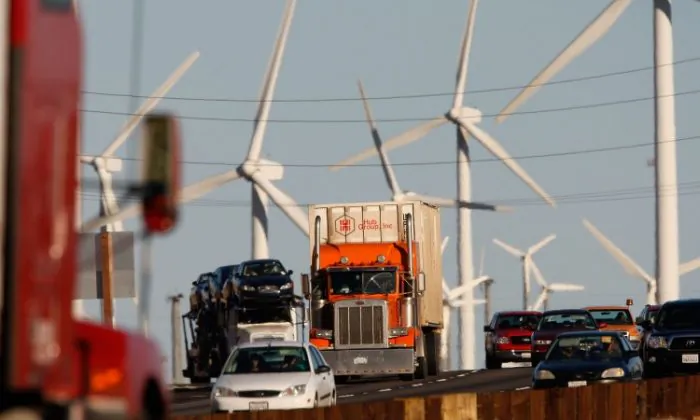 Xe hơi và xe tải xả khí thải đi qua một trang trại phong năng dọc theo đường xa lộ California. Người Mỹ bị phân cực sâu sắc trong niềm tin về biến đổi khí hậu, và các nhà nghiên cứu muốn biết lý do tại sao. (Ảnh: David McNew/Getty Images)