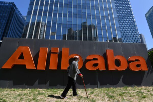 Một người phụ nữ đi ngang qua biển hiệu Alibaba bên ngoài văn phòng công ty ở Bắc Kinh hôm 13/04/2021. (Ảnh: Greg Baker/AFP/Getty Images)