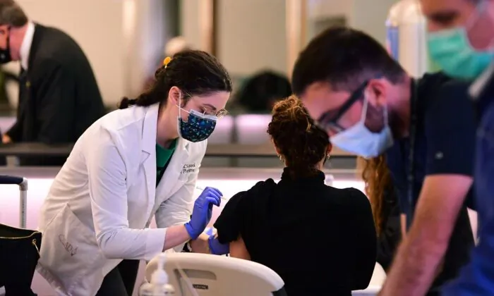 Một người được chích một mũi vaccine COVID-19 tại Phi trường Quốc tế Los Angeles ở Los Angeles, California, vào ngày 22/12/2021. (Ảnh: Frederic J. Brown/AFP qua Getty Images)