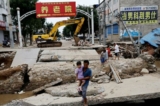 Một người đàn ông bế một bé gái đi qua cây cầu bị hư sau mưa lũ theo sau cơn bão Doksuri, ở Trác Châu, tỉnh Hà Bắc, Trung Quốc, hôm 07/08/2023. (Ảnh: Tingshu Wang/Reuters)
