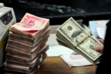 Một nhân viên ngân hàng Trung Quốc chuẩn bị đếm một chồng USD và các xấp tiền giấy 100 nhân dân tệ tại một ngân hàng ở Hợp Phì, tỉnh An Huy, Trung Quốc, hôm 09/03/2010. (Ảnh: STR/AFP qua Getty Images)