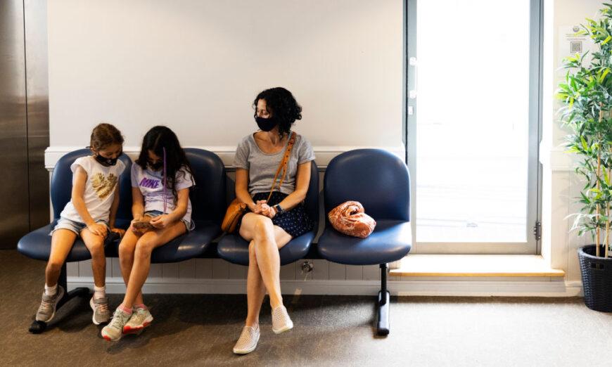 Cô Maria Persic ngồi cùng với các con gái là Millie Persic (bên trái) và Sofia Persic trong thời gian theo dõi sau khi chích vaccine Pfizer phòng COVID-19 tại phòng khám Sydney Road Family Medical Practice ở Balgowlah, Sydney, Úc vào ngày 11/01/2022. (Ảnh: Jenny Evans/Getty Images)