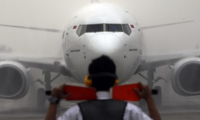 Một nhân viên phi trường hướng dẫn phi cơ của hãng hàng không Batik Air vào bãi đỗ trên đường băng trong lễ ra mắt hãng hàng không này tại Phi cơ Quốc tế Soekarno-Hatta ở Jakarta, Indonesia, vào ngày 25/04/2013. (Ảnh: Achmad Ibrahim/AP Photo)