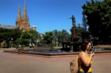 Một người phụ nữ nói chuyện điện thoại khi đi bộ qua Công viên Hyde ở Sydney, Úc, vào ngày 22/10/2019. (Ảnh: Lisa Maree Williams/Getty Images)