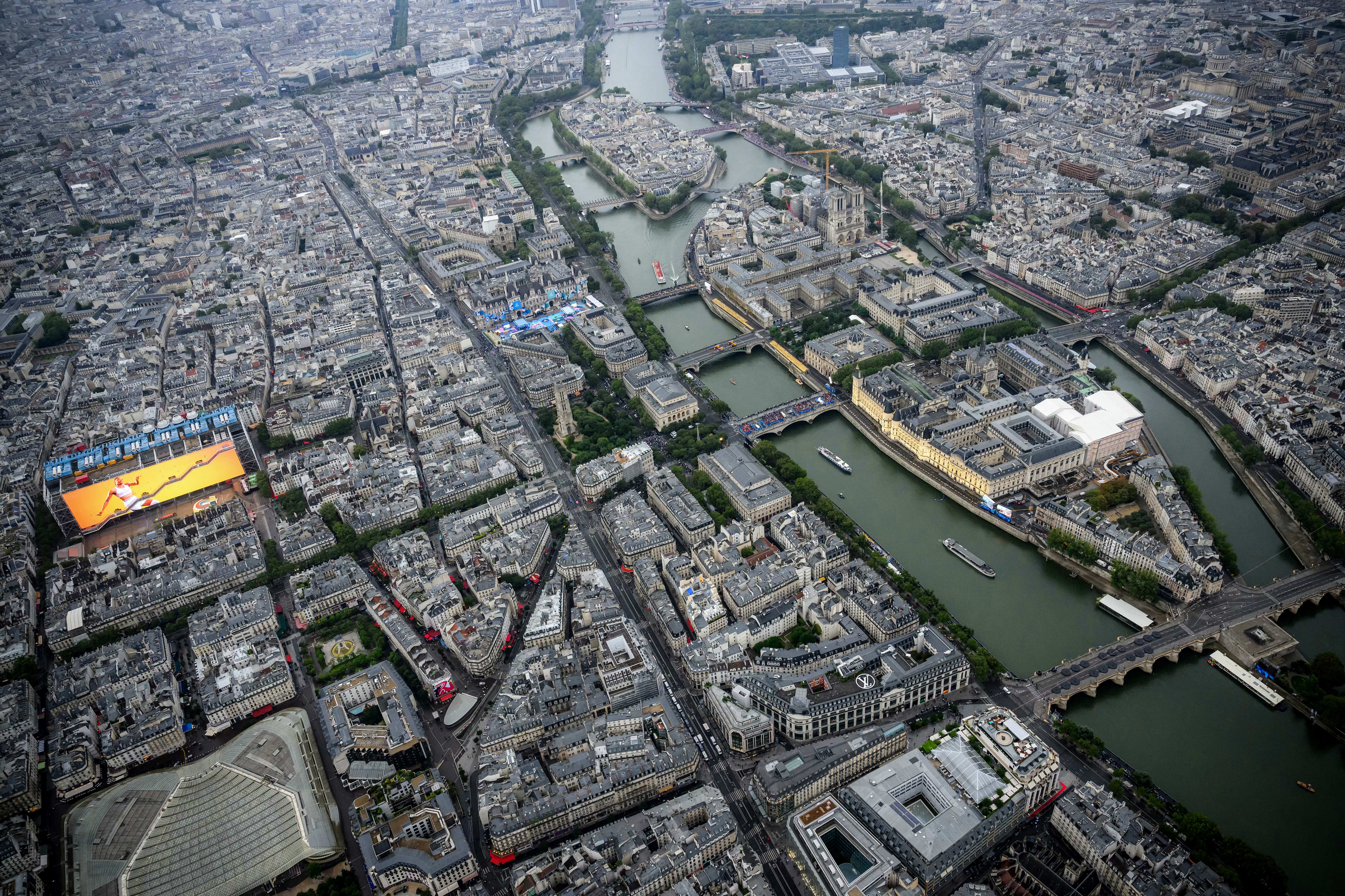 Quang cảnh từ trên cao nhìn về Nhà thờ Đức Bà Paris khi thuyền của các đoàn thể thao di chuyển trên sông Seine qua Đảo Ile de la Cité (phía trước bên phải), Đảo Saint-Louis (phía sau bên phải) và bảo tàng Centre Pompidou (bên trái) trong buổi lễ khai mạc Thế vận hội Paris 2024 tại Paris, hôm 26/07/2024. (Ảnh: Lionel Bonaventure/Pool/AFP qua Getty Images)